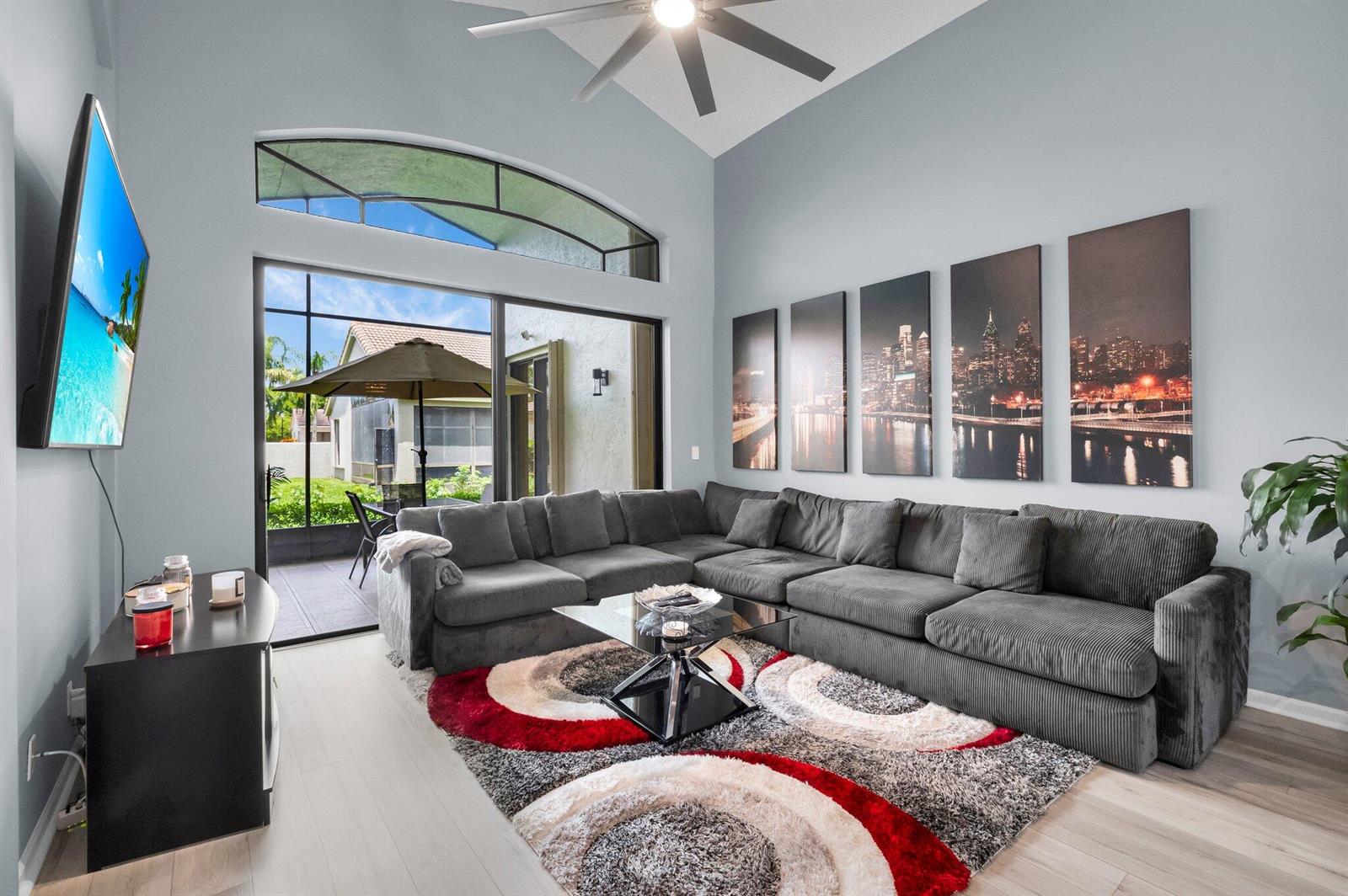 A living room features a large gray sectional, a patterned rug, and a sliding glass door — 10393 Lexington Circle S, Boynton Beach FL 33436, BOYNTON BEACH, FL