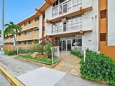 A multi-story apartment building features balconies, a glass-front entrance, and landscaped greenery — 3881 W FLAGLER STREET UNIT 102, MIAMI, FL