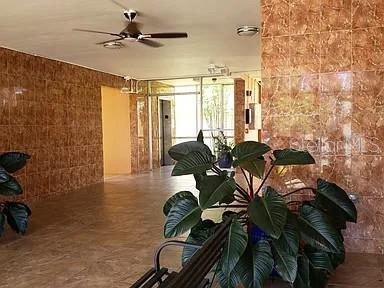 A lobby area features brown tiled walls, a ceiling fan, and a large potted plant — 3881 W FLAGLER STREET UNIT 102, MIAMI, FL