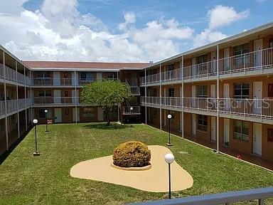 An exterior view of a multi-story apartment complex with a central courtyard and lawn — 3881 W FLAGLER STREET UNIT 102, MIAMI, FL
