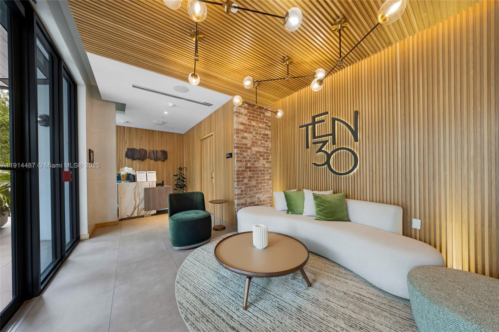 A modern lobby features a curved sofa, green accent chair, and wood-slatted walls and ceiling — 1030 15th St # 306, Miami Beach FL 33139, MIAMI BEACH, FL