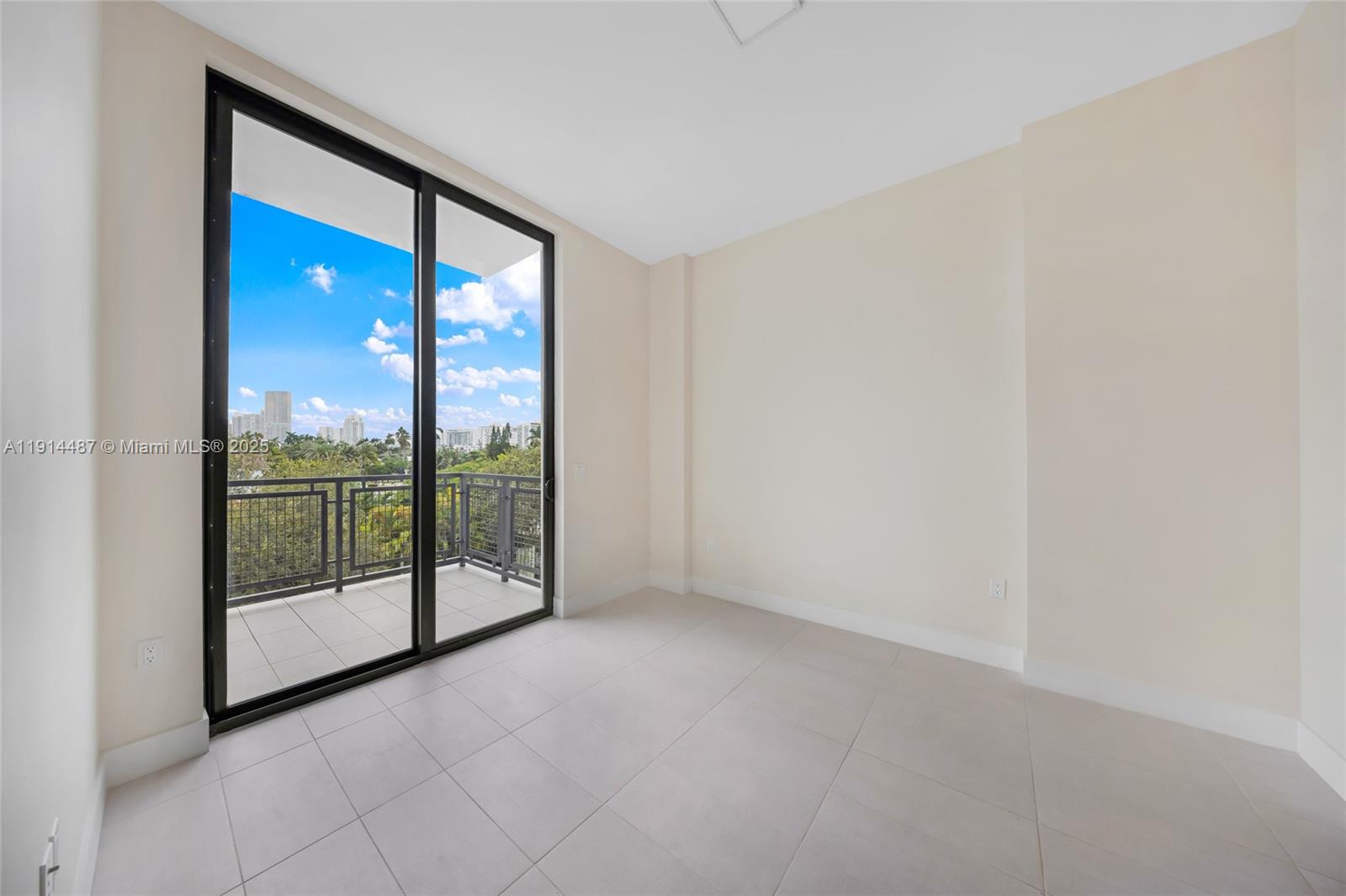 An empty room with light tile floors, beige walls, and a sliding glass door to a balcony — 1030 15th St # 306, Miami Beach FL 33139, MIAMI BEACH, FL
