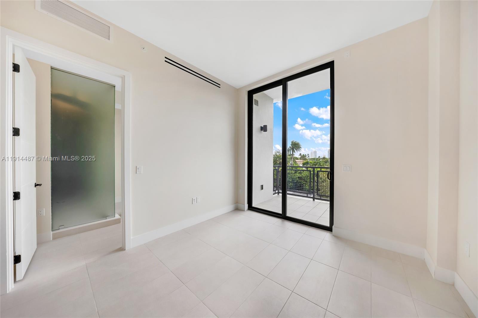 An empty room with light tile floors, a frosted glass door, and a sliding balcony door — 1030 15th St # 306, Miami Beach FL 33139, MIAMI BEACH, FL