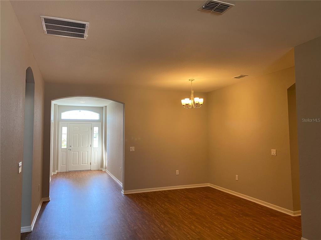 An interior view shows a dining area with wood-look flooring and a hanging chandelier — 481 PHEASANT DRIVE, HAINES CITY, FL