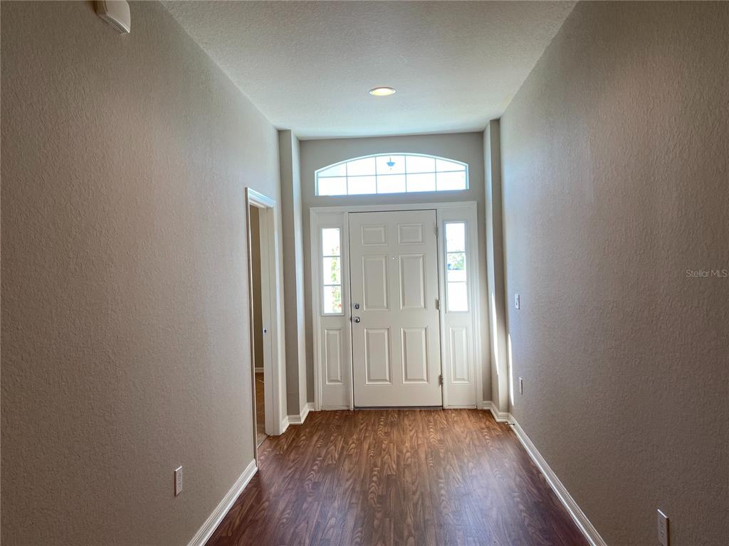 A foyer features wood-look flooring, beige walls, and a white front door with sidelights — 481 PHEASANT DRIVE, HAINES CITY, FL