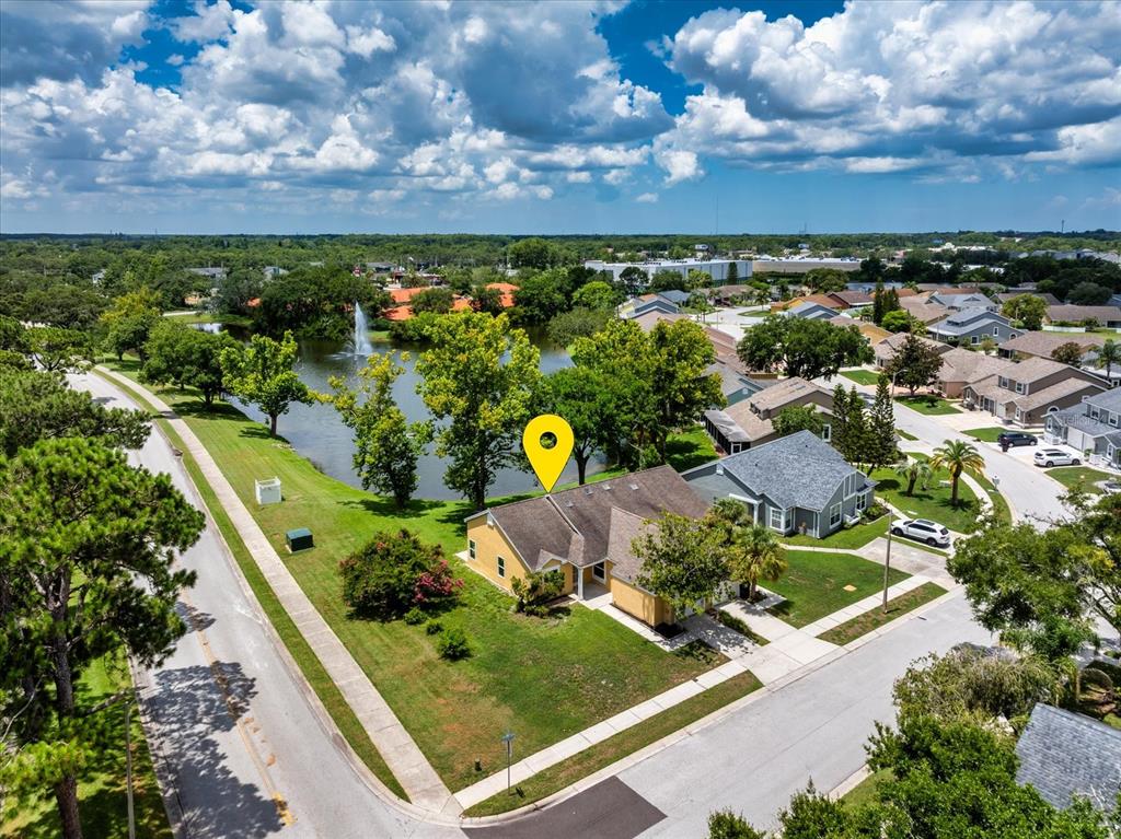 An aerial view shows a yellow house with a brown roof next to a pond — 7728 BALHARBOUR DRIVE, NEW PORT RICHEY, FL