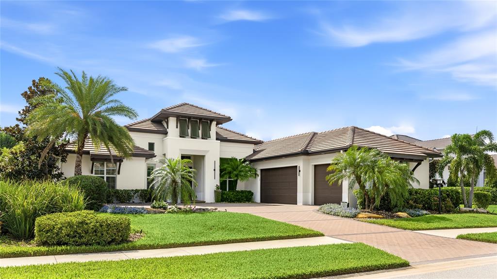 A white house with a brown tile roof and a paved driveway features two garages — 804 CROSSWIND AVENUE, SARASOTA, FL