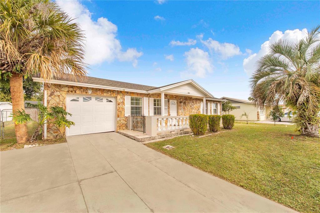 A single-story house with a stone facade, a white garage door, and a front porch — 666 FLORIDA PARKWAY, KISSIMMEE, FL