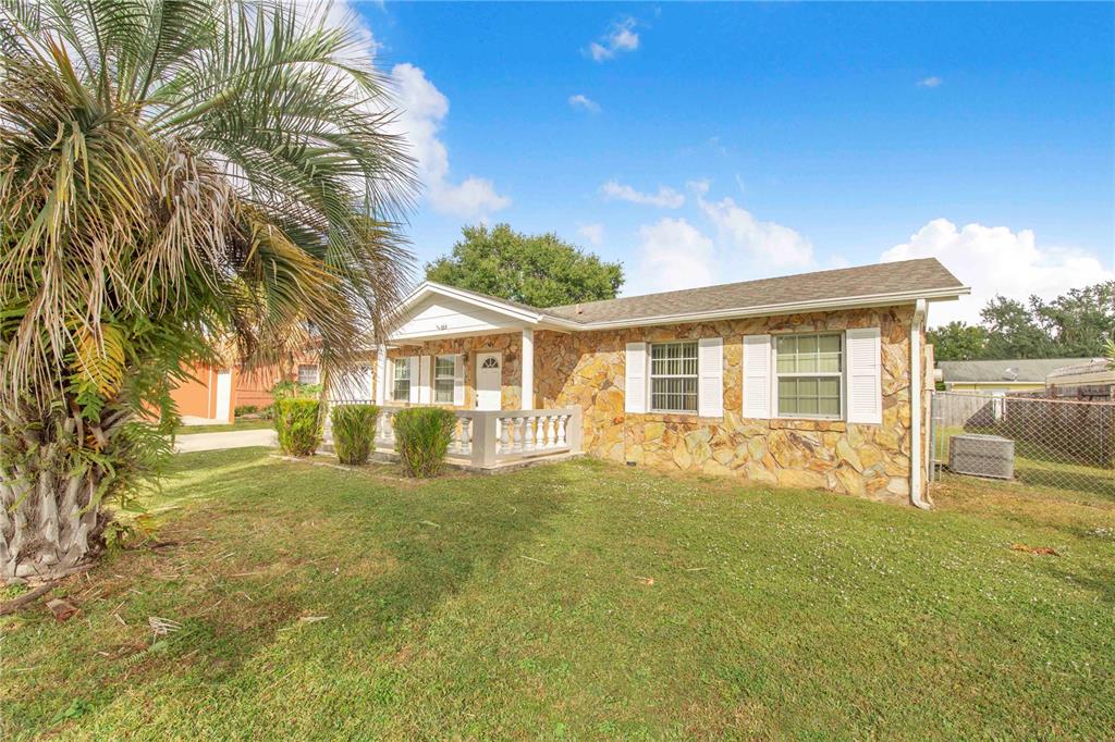 A single-story house with a stone facade, a front porch, and a large palm tree — 666 FLORIDA PARKWAY, KISSIMMEE, FL