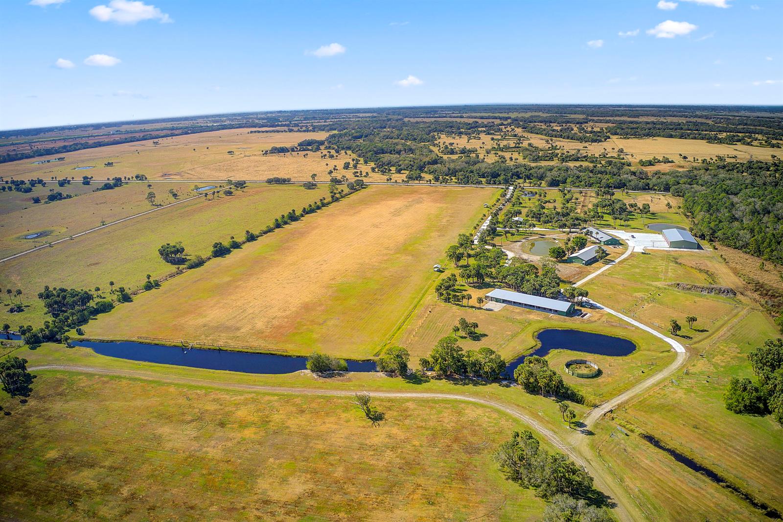 An aerial view shows a large rural property with pastures, several outbuildings, and two ponds — 30003 SW Martin Highway, Okeechobee FL 34974, OKEECHOBEE, FL