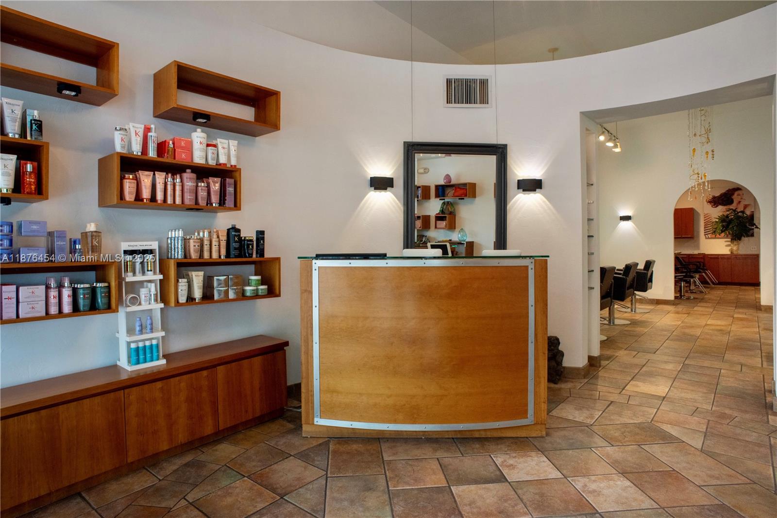 A salon reception area features a wooden desk, product display shelves, and tiled flooring — 345 MIRACLE MILE, Coral Gables FL 33134, CORAL GABLES, FL