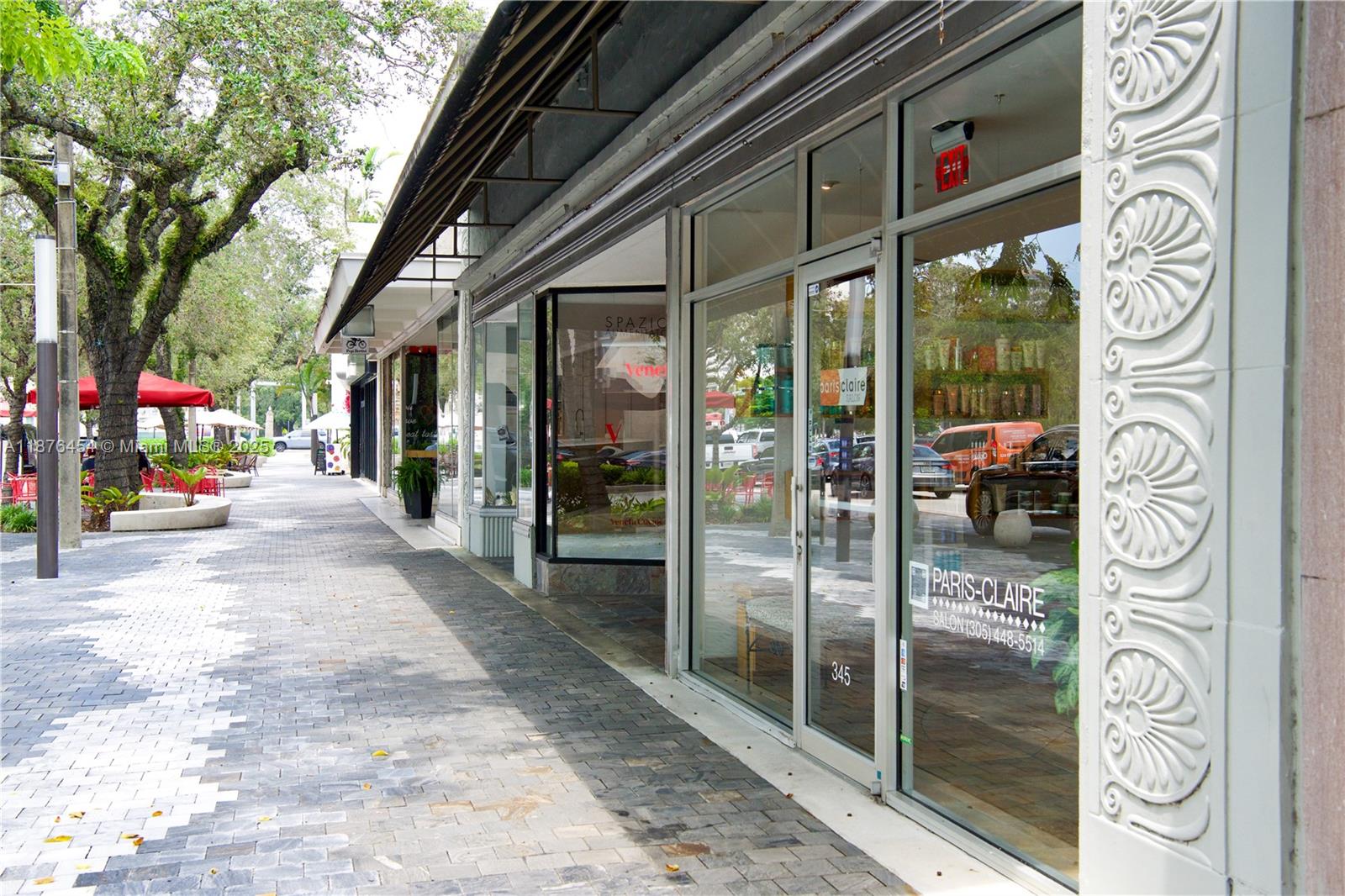 A sidewalk runs along the glass storefronts of a commercial building with decorative exterior columns — 345 MIRACLE MILE, Coral Gables FL 33134, CORAL GABLES, FL