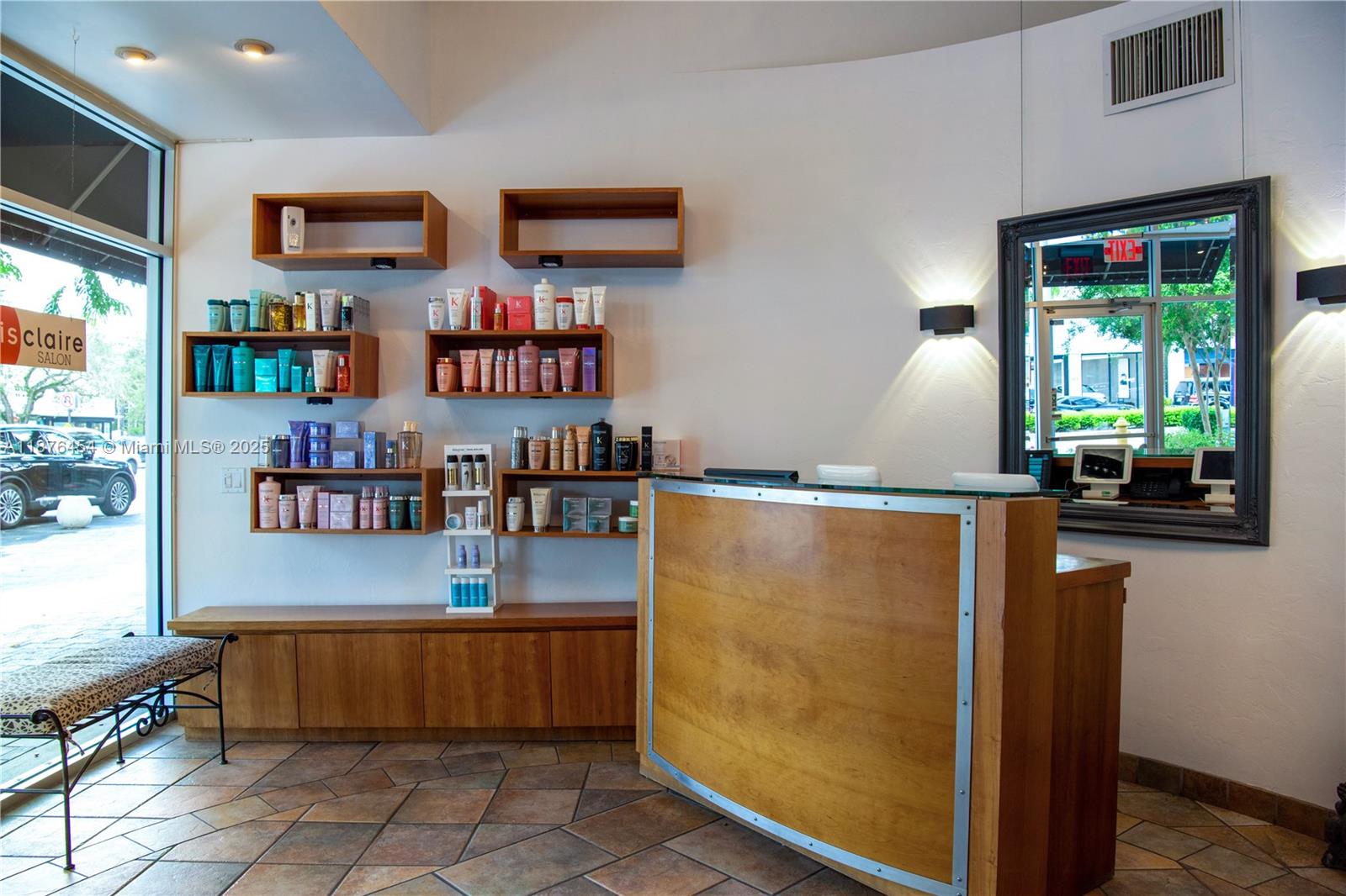A salon reception area features a wooden desk, wall-mounted shelving, and a large framed mirror — 345 MIRACLE MILE, Coral Gables FL 33134, CORAL GABLES, FL
