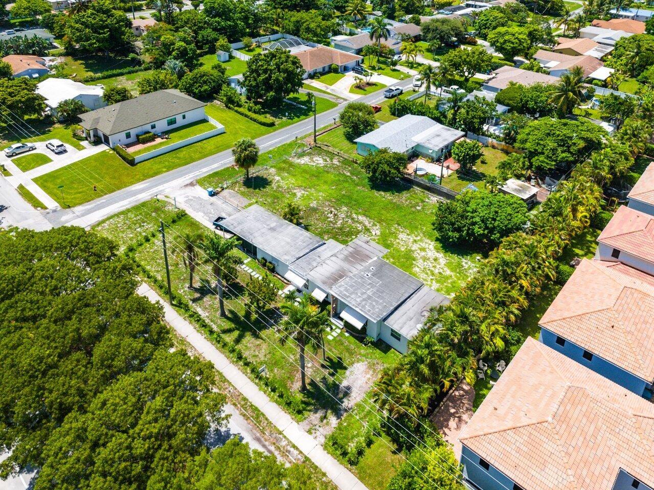 An aerial view shows a single-story house with a flat roof surrounded by green lawns — 3650 SE 2nd Court, Boynton Beach FL 33435, BOYNTON BEACH, FL