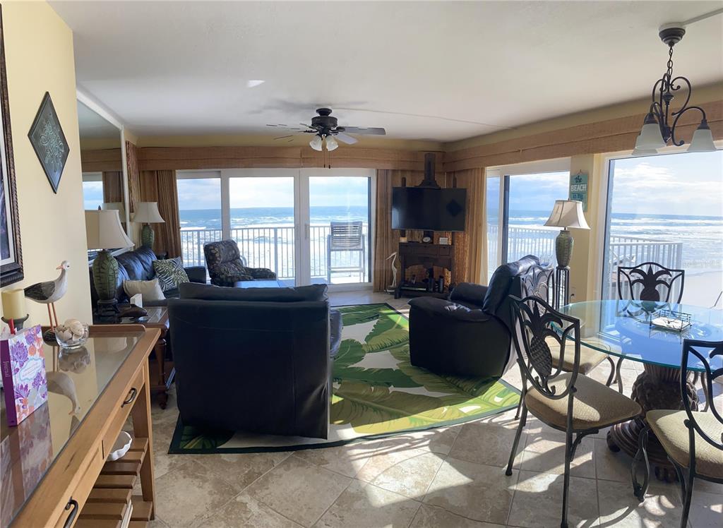 A living and dining area with tile floors, leather furniture, and ocean views through sliding doors — 1571 S ATLANTIC AVENUE UNIT 309, NEW SMYRNA BEACH, FL