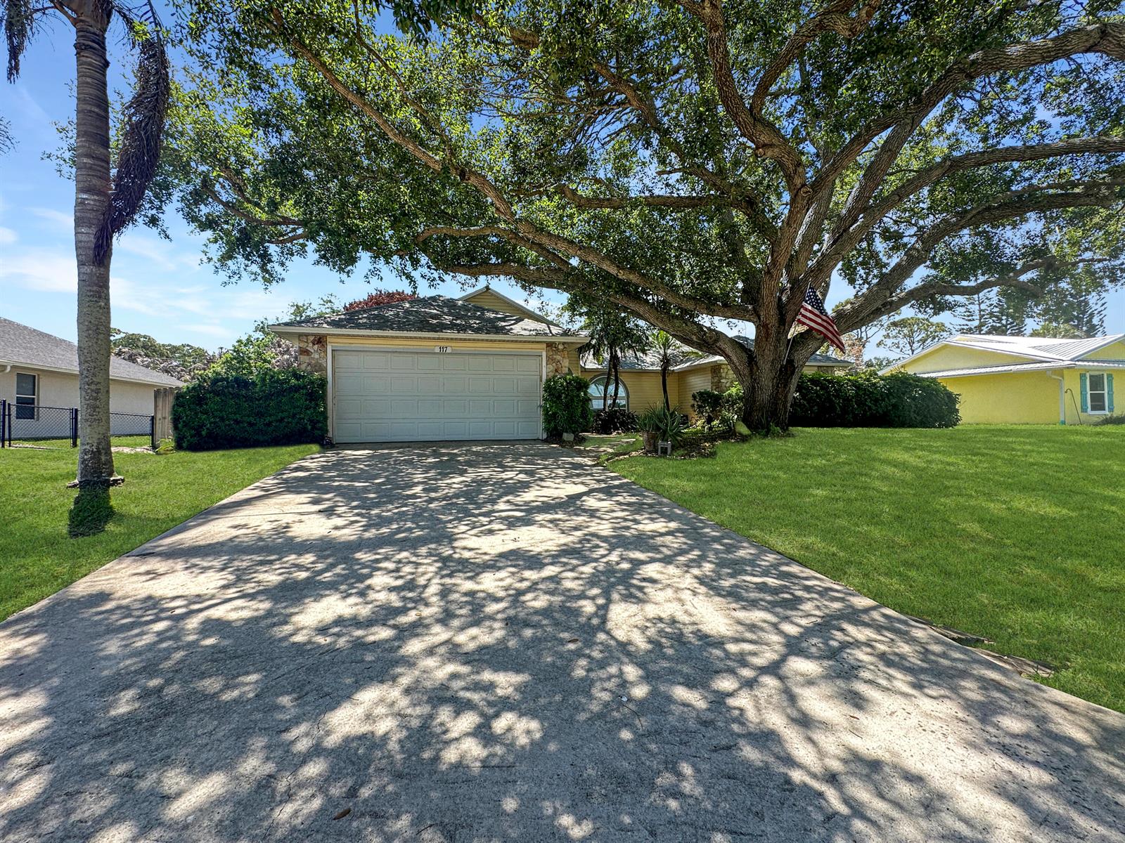 A single-story house with a concrete driveway, a large oak tree, and a garage — 117 Hinchman Avenue, Sebastian FL 32958, SEBASTIAN, FL