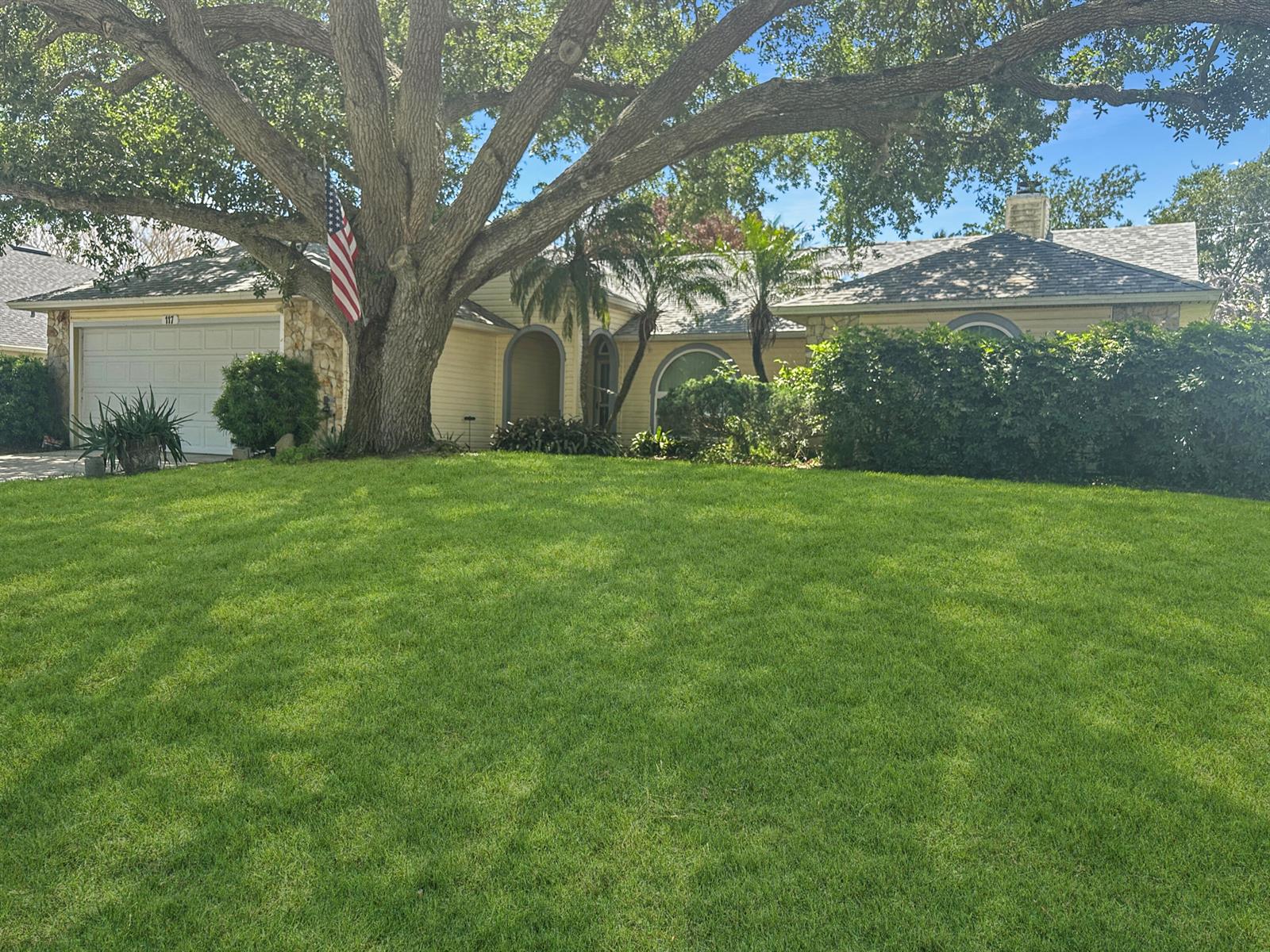 A single-story house with a large oak tree, a front lawn, and an American flag — 117 Hinchman Avenue, Sebastian FL 32958, SEBASTIAN, FL
