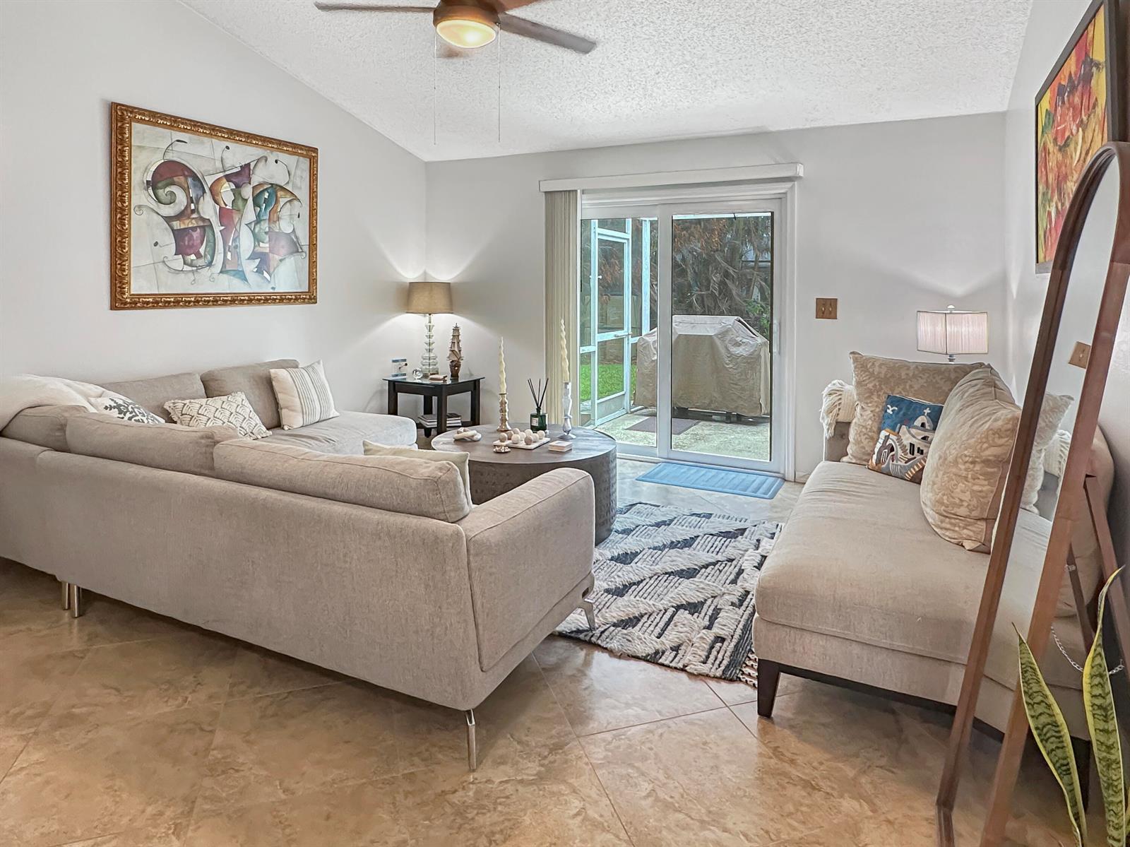 A living room features a sectional sofa, a patterned rug, and sliding glass patio doors — 117 Hinchman Avenue, Sebastian FL 32958, SEBASTIAN, FL