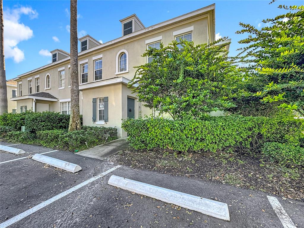 A beige multi-story townhouse exterior features a front entrance, parking spaces, and surrounding landscaping — 760 SIENA PALM DRIVE UNIT 205, KISSIMMEE, FL