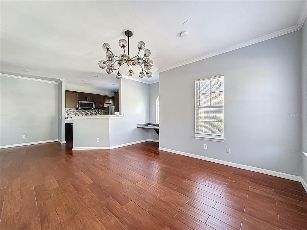 A dining area with wood-look tile flooring, a modern chandelier, and an adjacent kitchen — 760 SIENA PALM DRIVE UNIT 205, KISSIMMEE, FL