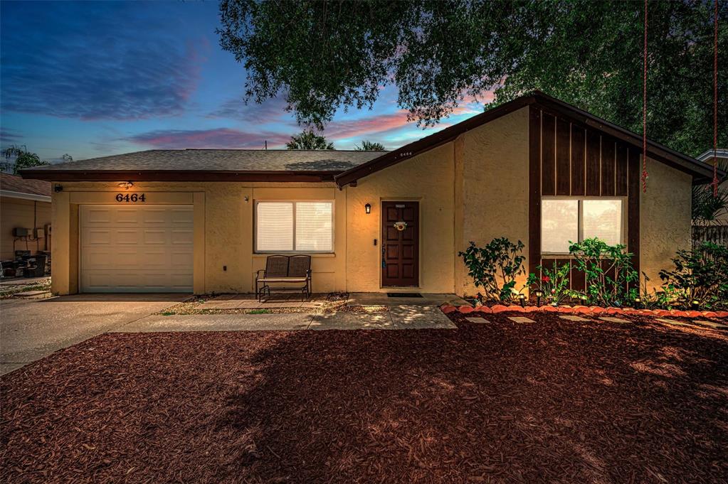A single-story house with a garage, a brown front door, and a mulched front yard — 6464 107TH TERRACE N, PINELLAS PARK, FL