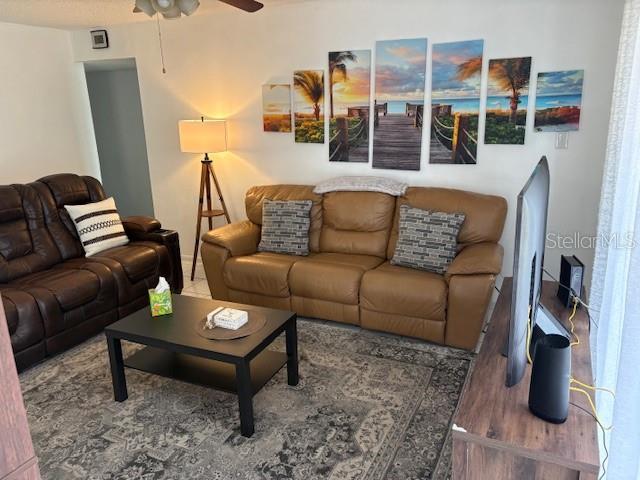 A living room features a brown leather sofa, a dark coffee table, and wall art — 2625 STATE ROAD 590 UNIT 2413, CLEARWATER, FL