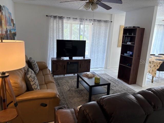 A living room features a brown leather sofa, a television on a console, and shelving — 2625 STATE ROAD 590 UNIT 2413, CLEARWATER, FL