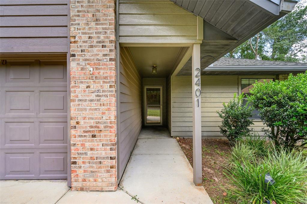 The exterior view shows a covered entryway with a brick column and a front door — 2401 NW 69TH TERRACE, GAINESVILLE, FL