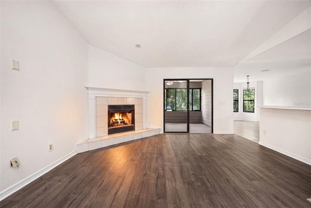 A living room features wood-look flooring, a corner fireplace with tile surround, and sliding glass doors — 2401 NW 69TH TERRACE, GAINESVILLE, FL