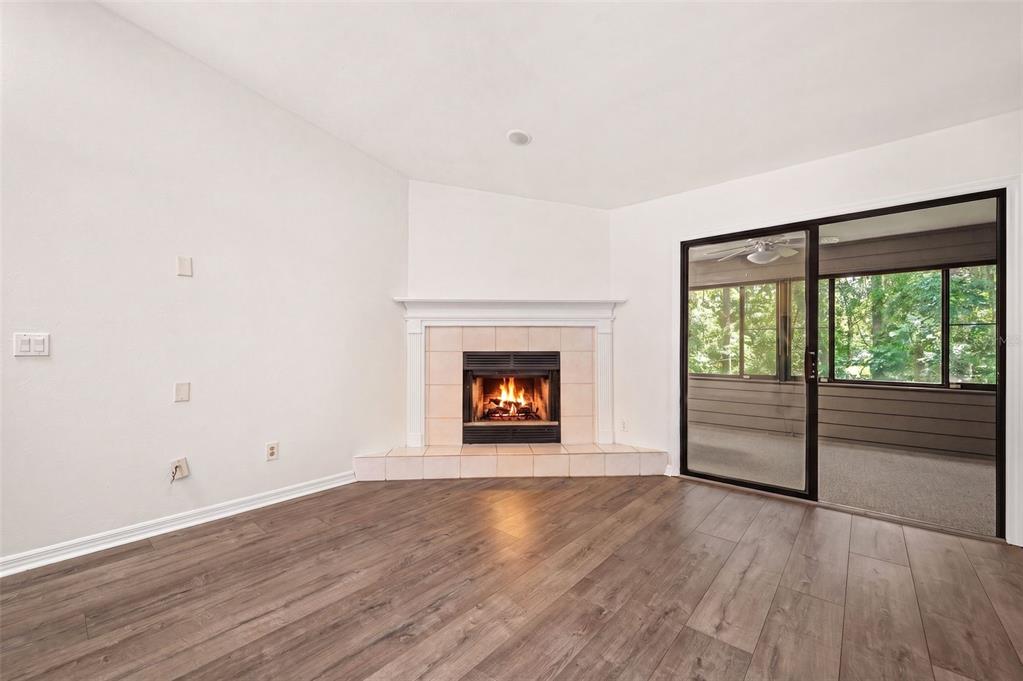 A living room features wood-look flooring, a corner fireplace with tile surround, and sliding glass doors — 2401 NW 69TH TERRACE, GAINESVILLE, FL