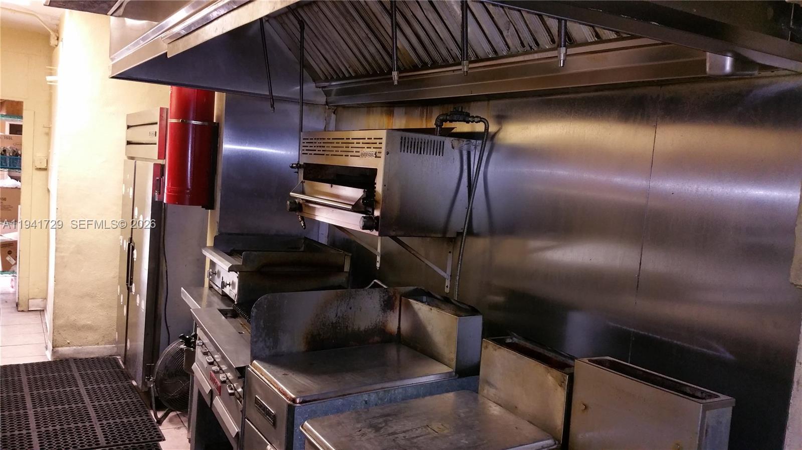 A commercial kitchen features stainless steel appliances, a ventilation hood, and a wall-mounted salamander broiler — 13914 NW 7th Ave, Miami FL 33168, MIAMI, FL