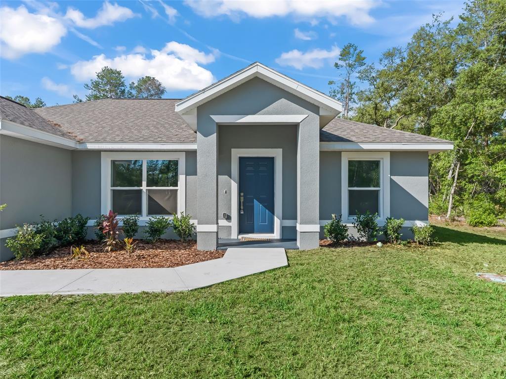 The exterior of a gray single-story house features a blue front door and walkway — 4994 SW 166TH LOOP, OCALA, FL