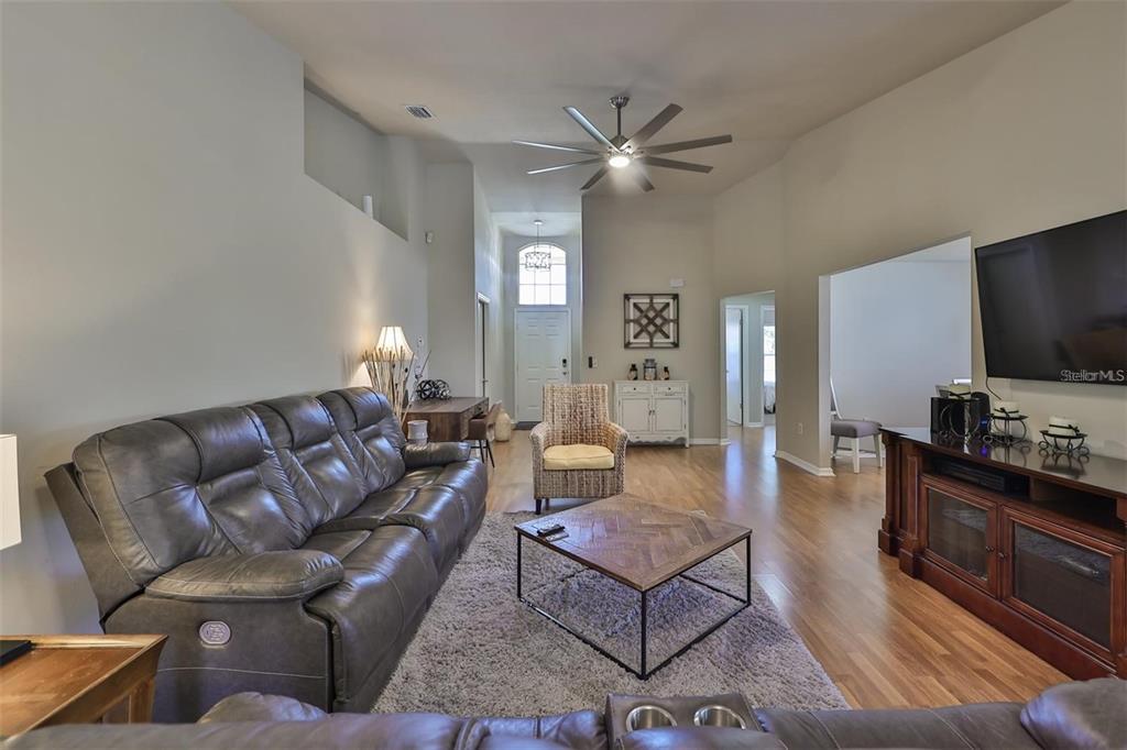 A living room features a gray leather sofa, a wooden coffee table, and hardwood floors — 128 LOOKOUT DRIVE, APOLLO BEACH, FL