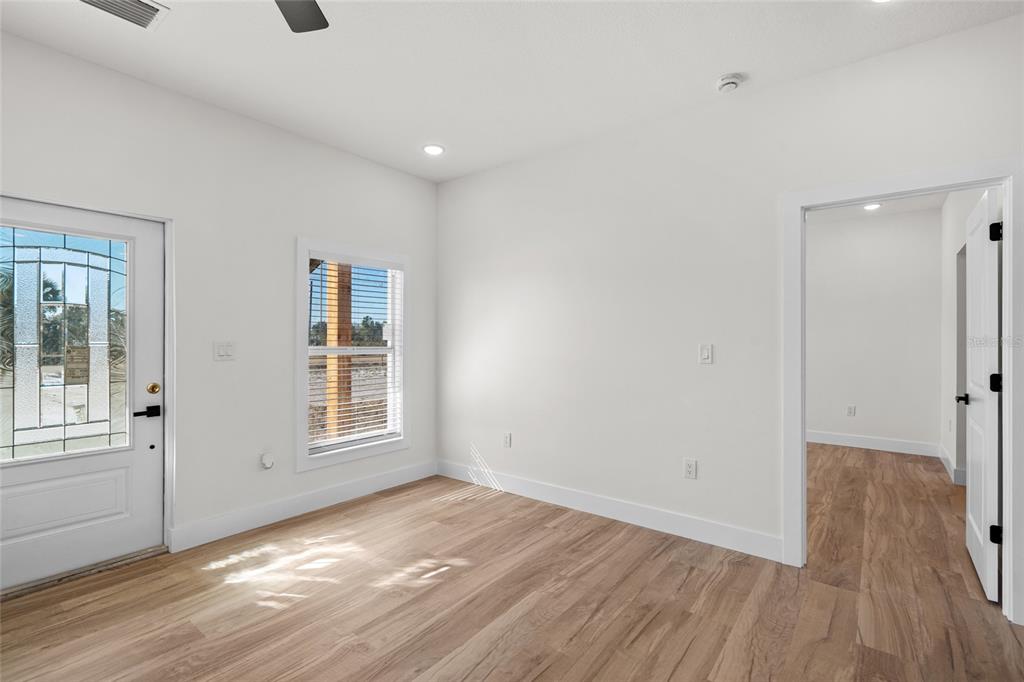 An empty room with light wood-look flooring, white walls, a glass-paneled door, and a doorway — 17428 NW 288TH STREET, OKEECHOBEE, FL