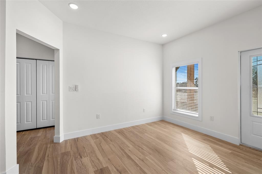 An empty room with light wood flooring, white walls, a window, and a closet door — 17428 NW 288TH STREET, OKEECHOBEE, FL