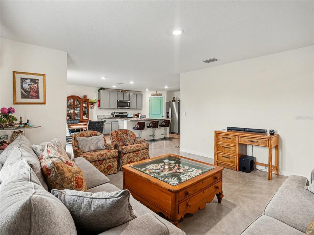 A living room with a glass-topped coffee table opens into a kitchen with bar seating — 4114 DOVETAIL LANE, PALMETTO, FL