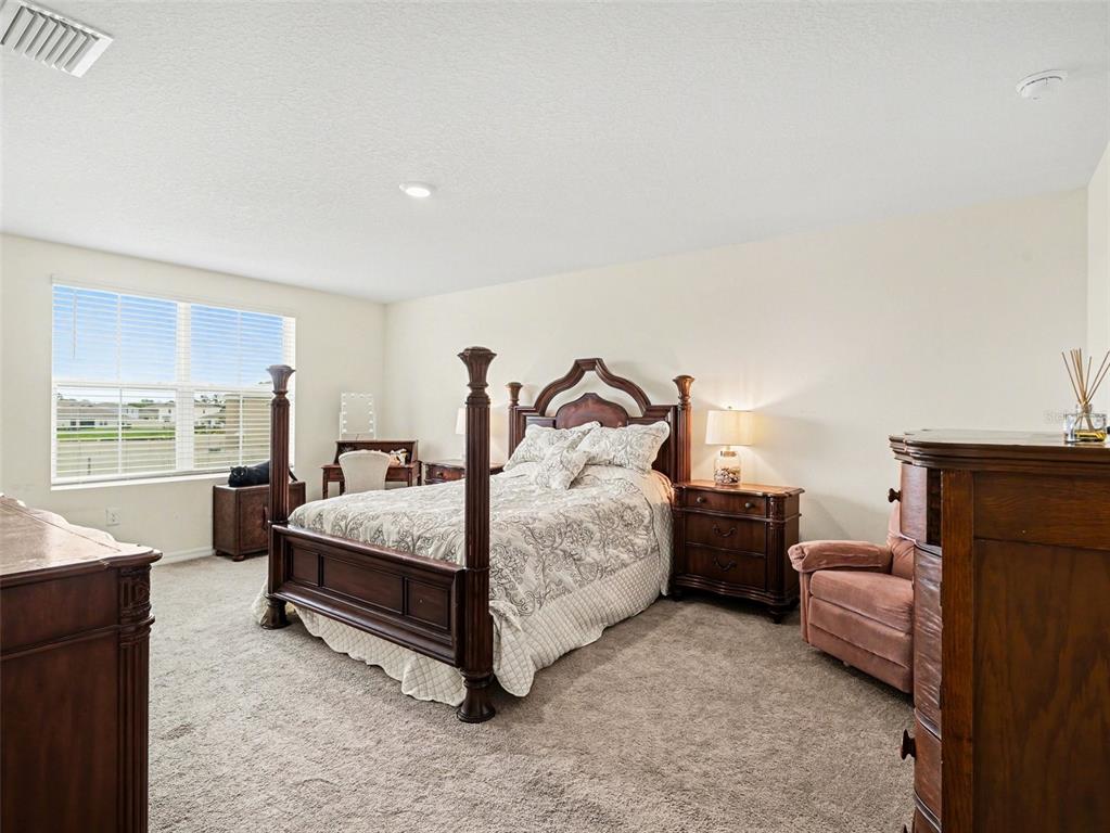 A bedroom features a dark wood four-poster bed, matching nightstands, and a pink armchair — 4114 DOVETAIL LANE, PALMETTO, FL