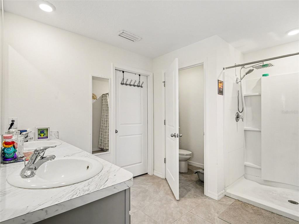 A bathroom features a double vanity with marble-look counters, a walk-in shower, and a toilet closet — 4114 DOVETAIL LANE, PALMETTO, FL