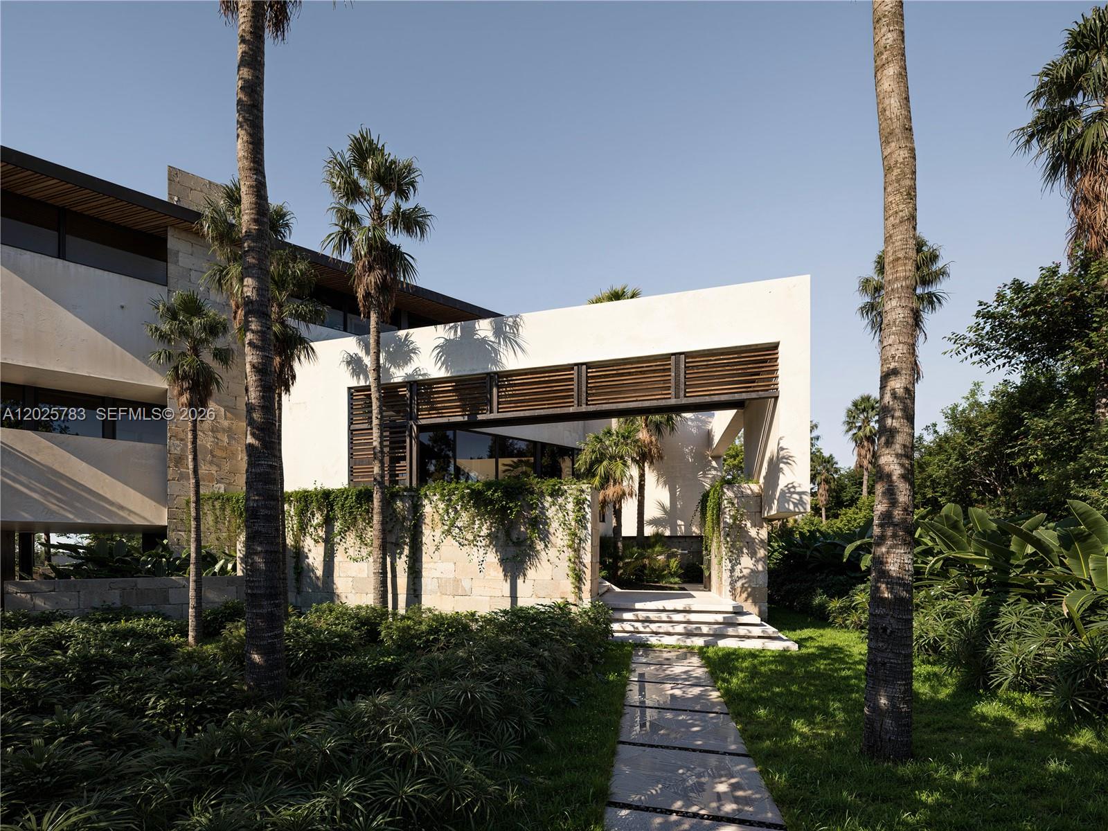 A modern house exterior features stone walls, wooden louvers, and a stone walkway with palms — 6941 Sunrise Ct, Coral Gables FL 33133, CORAL GABLES, FL