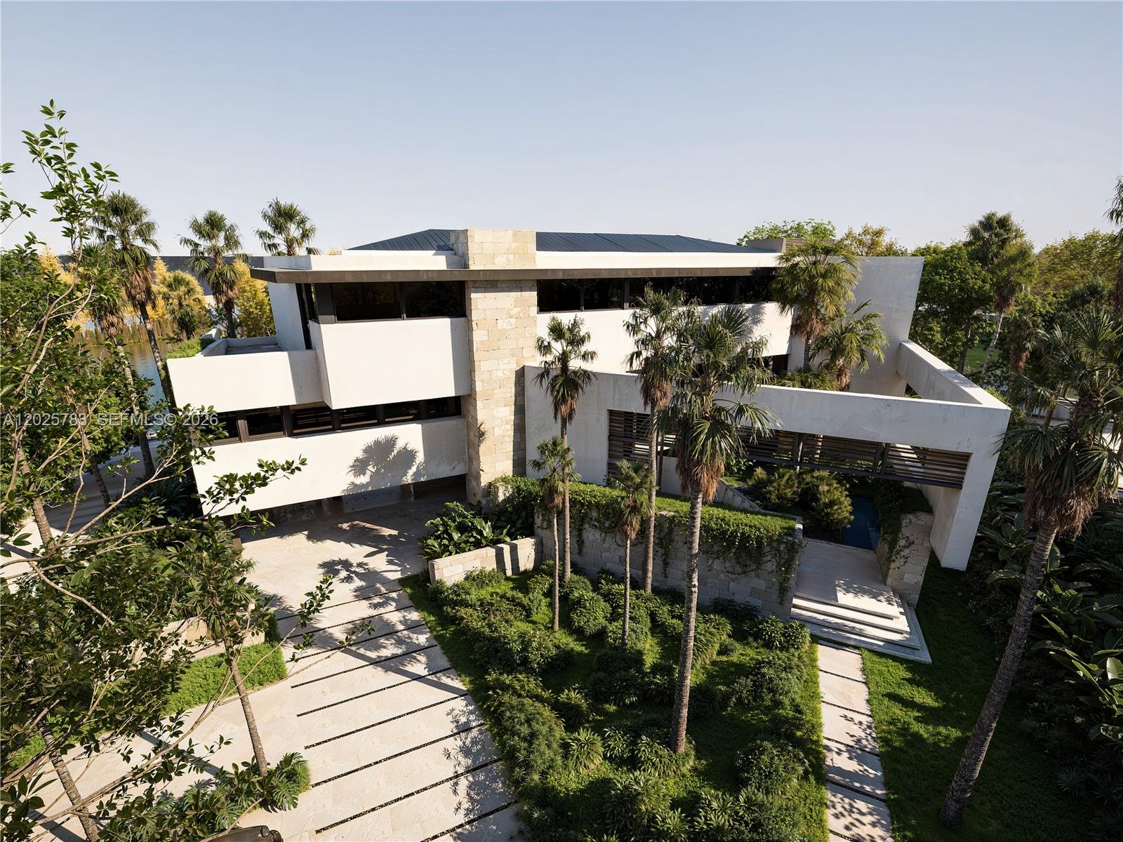 An aerial view of a modern multi-story home with stone accents and lush landscaping — 6941 Sunrise Ct, Coral Gables FL 33133, CORAL GABLES, FL