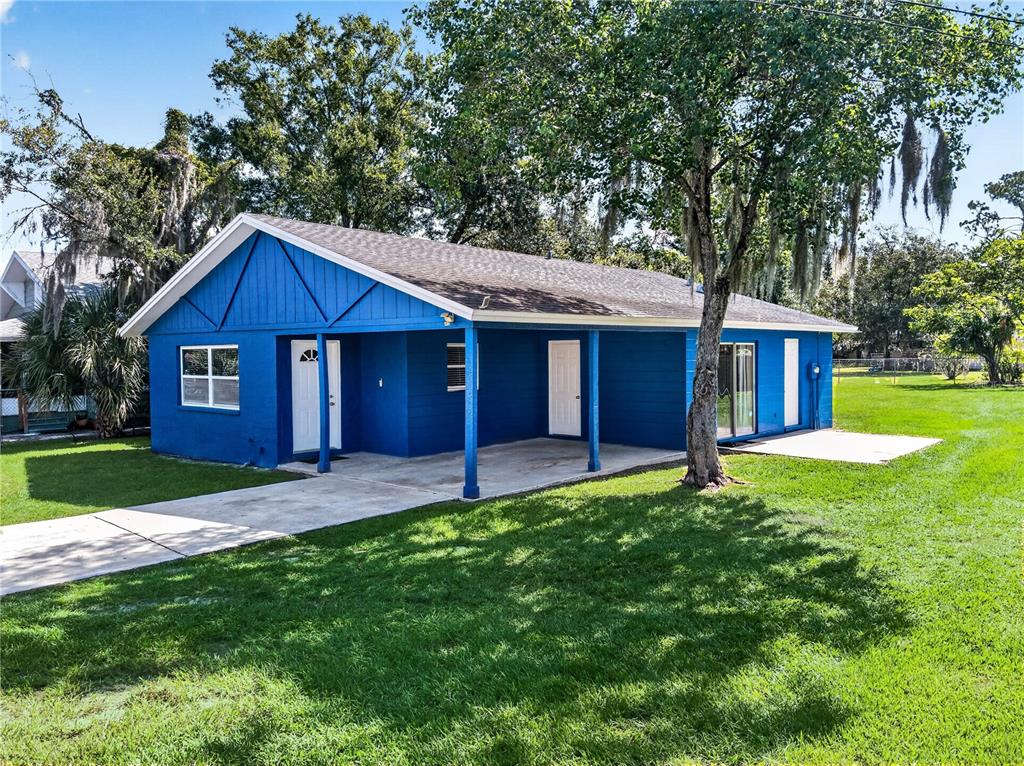 A blue, single-story house with a covered porch and a concrete driveway sits on grass — 2509 N FLORIDA AVENUE, LAKELAND, FL