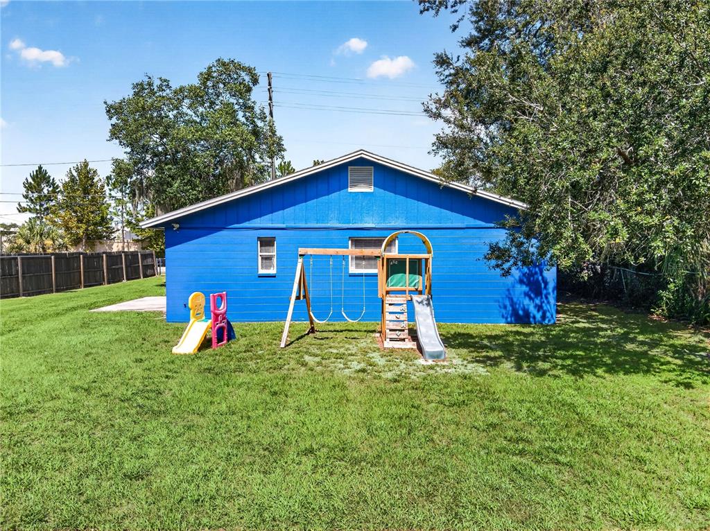 A bright blue house exterior features a backyard with a swing set and slide — 2509 N FLORIDA AVENUE, LAKELAND, FL