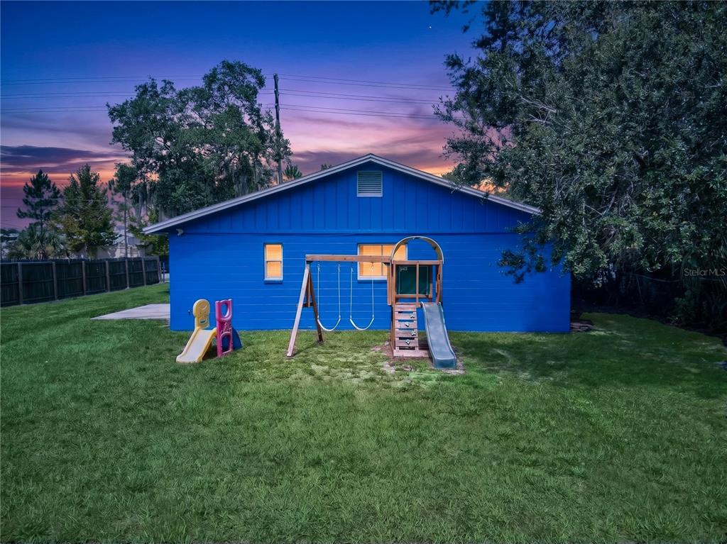 The exterior of a blue house features a backyard with a swing set and slide — 2509 N FLORIDA AVENUE, LAKELAND, FL