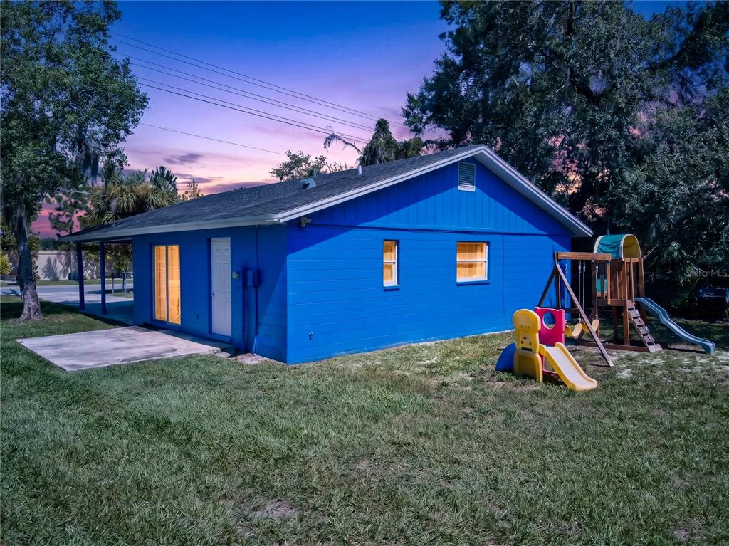 A bright blue, single-story house exterior features a backyard playground and a concrete patio — 2509 N FLORIDA AVENUE, LAKELAND, FL