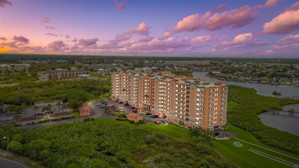 An aerial view of a multi-story apartment building surrounded by green space and a waterway — 4516 SEAGULL DRIVE UNIT 804, NEW PORT RICHEY, FL