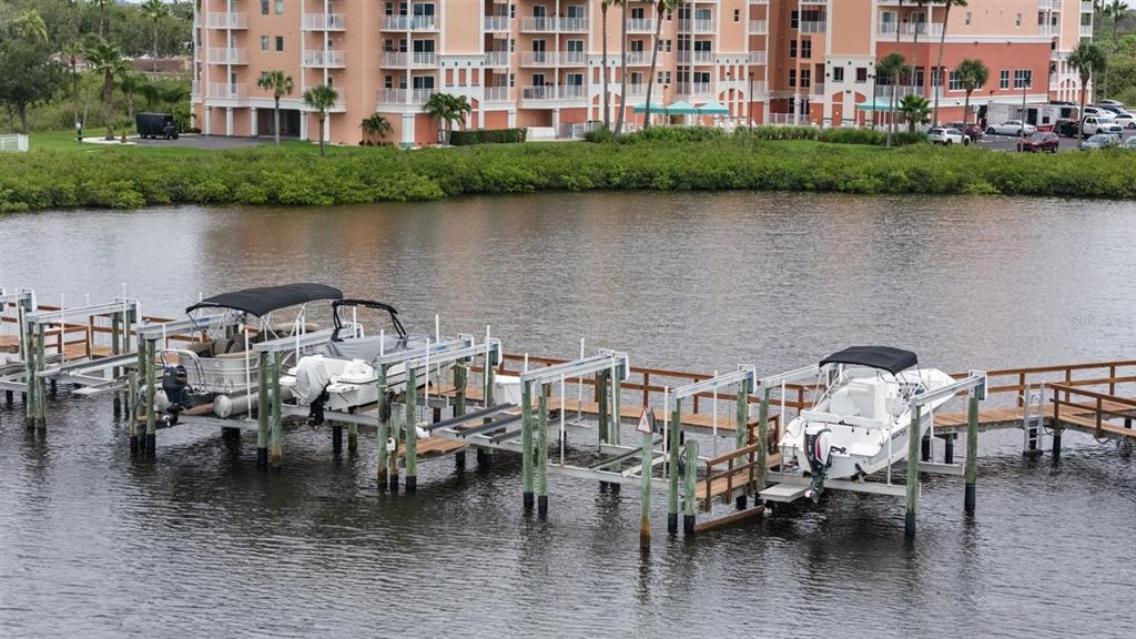 A boat dock with two boats on lifts extends into a canal near a building — 4516 SEAGULL DRIVE UNIT 804, NEW PORT RICHEY, FL