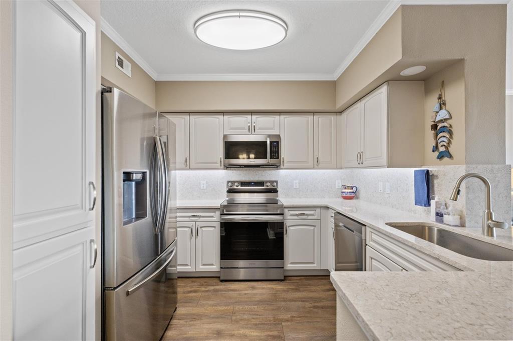 A kitchen with stainless steel appliances, white cabinets, and light-colored quartz countertops — 4516 SEAGULL DRIVE UNIT 804, NEW PORT RICHEY, FL