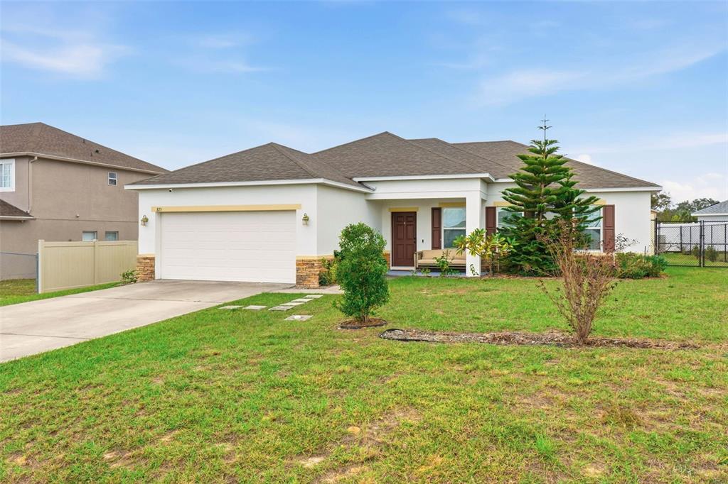 A single-story house with a white stucco exterior, a two-car garage, and a front lawn — 875 FRASER DRIVE, KISSIMMEE, FL