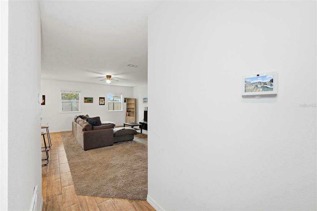 A view from a hallway into a living room with tile flooring and carpet — 875 FRASER DRIVE, KISSIMMEE, FL