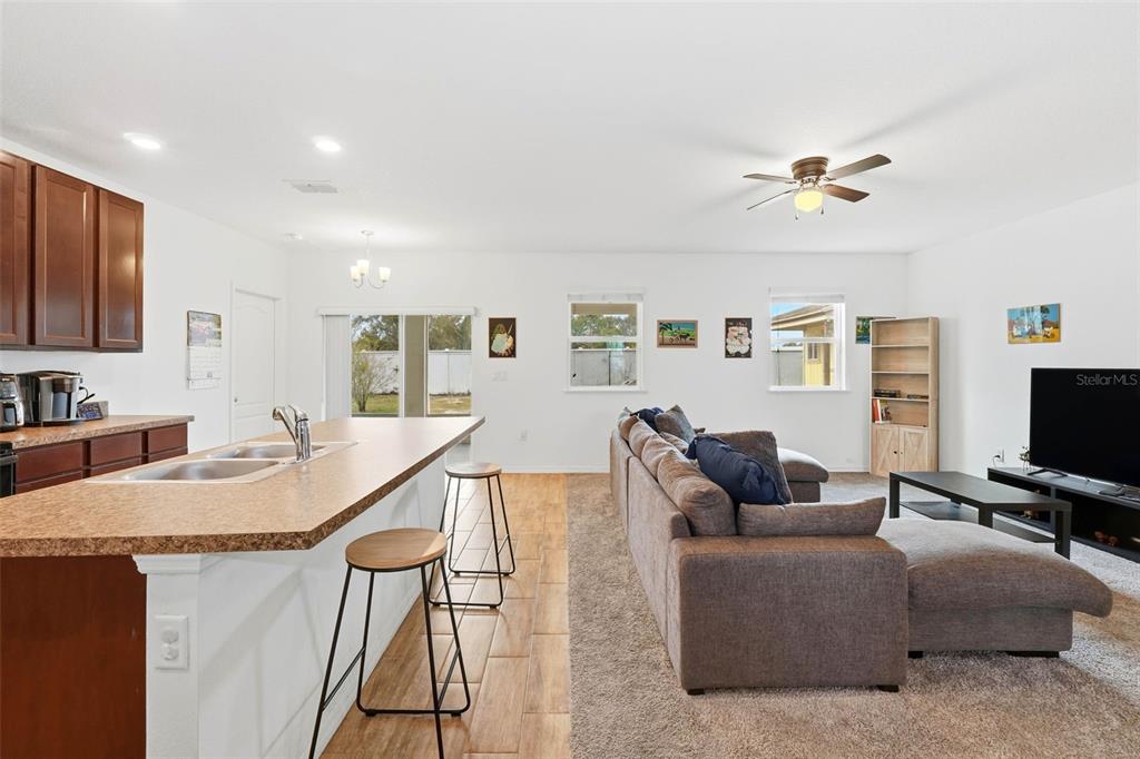 An open-concept kitchen with a breakfast bar overlooks a living room with a sectional sofa — 875 FRASER DRIVE, KISSIMMEE, FL